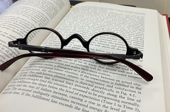 brown-framed eyeglasses on top of opened book